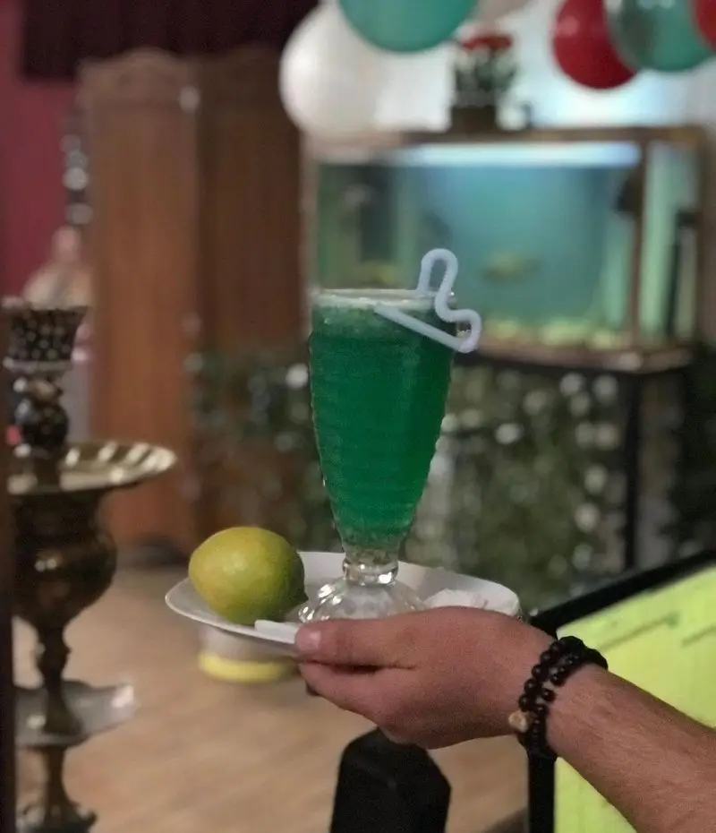 سرو نوشیدنی خنک سبز رنگ و تازه با لیمو در کافه رستوران کمند، تجربه‌ای دلنشین در فضایی آرامش‌بخش.