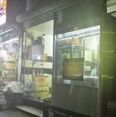 ورودی کبابی کبابسرای نیک در شب، با ویترین روشن نمایش میوه‌ها و تابلوی حلیم و صبحانه تازه با نان داغ.