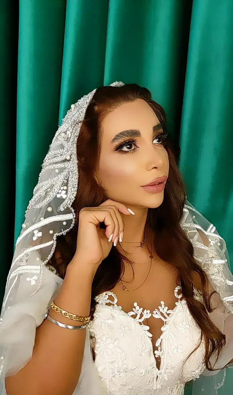 عکس مدل آرایش عروس با میکاپ لایت و شیک و تور عروس کار شده با مروارید به همراه اکسسوری و دستبند طلا در سالن زیبایی تخصصی