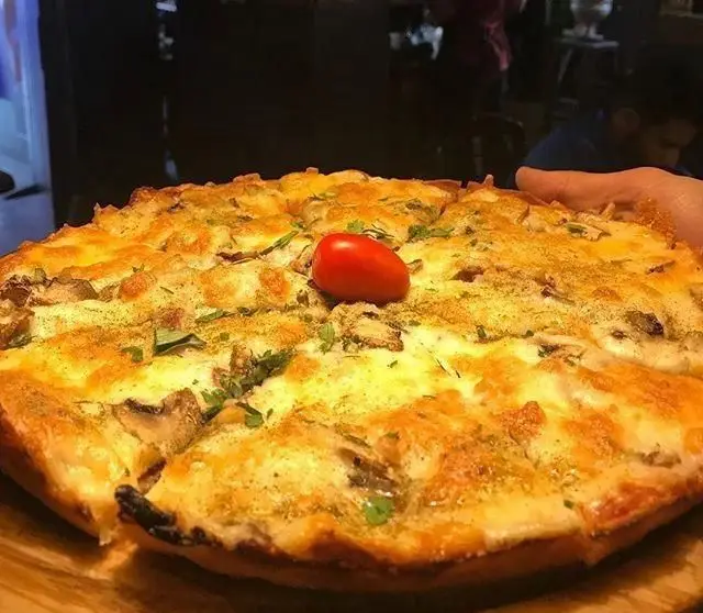 پیتزا قارچ و پنیر خوشمزه و داغ کافی شاپ گلدون با چاشنی سبزیجات معطر و یک گوجه گیلاسی روی آن، بهترین انتخاب برای غذای کافه.