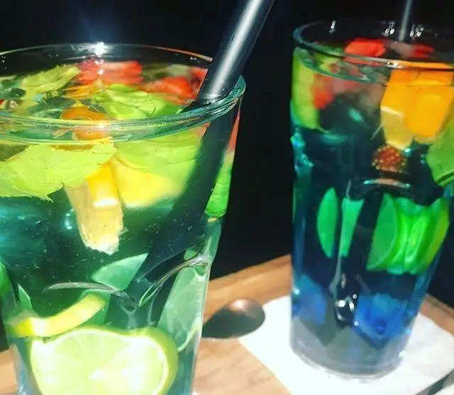 نوشیدنی‌های خنک و میوه‌ای کافی شاپ گلدون: دو لیوان کوکتل/موکتل با طعم لیمو، پرتقال، نعناع و توت فرنگی، ایده‌آل برای تابستان.