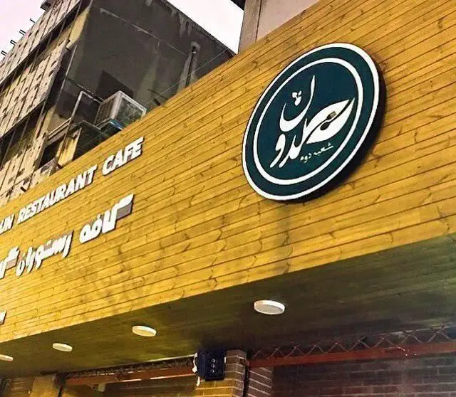 نمای بیرونی کافی شاپ و کافه رستوران گلدون شعبه دو، با تابلوی دایره‌ای سبز و نام گلدون به خط فارسی روی سردر چوبی مدرن.