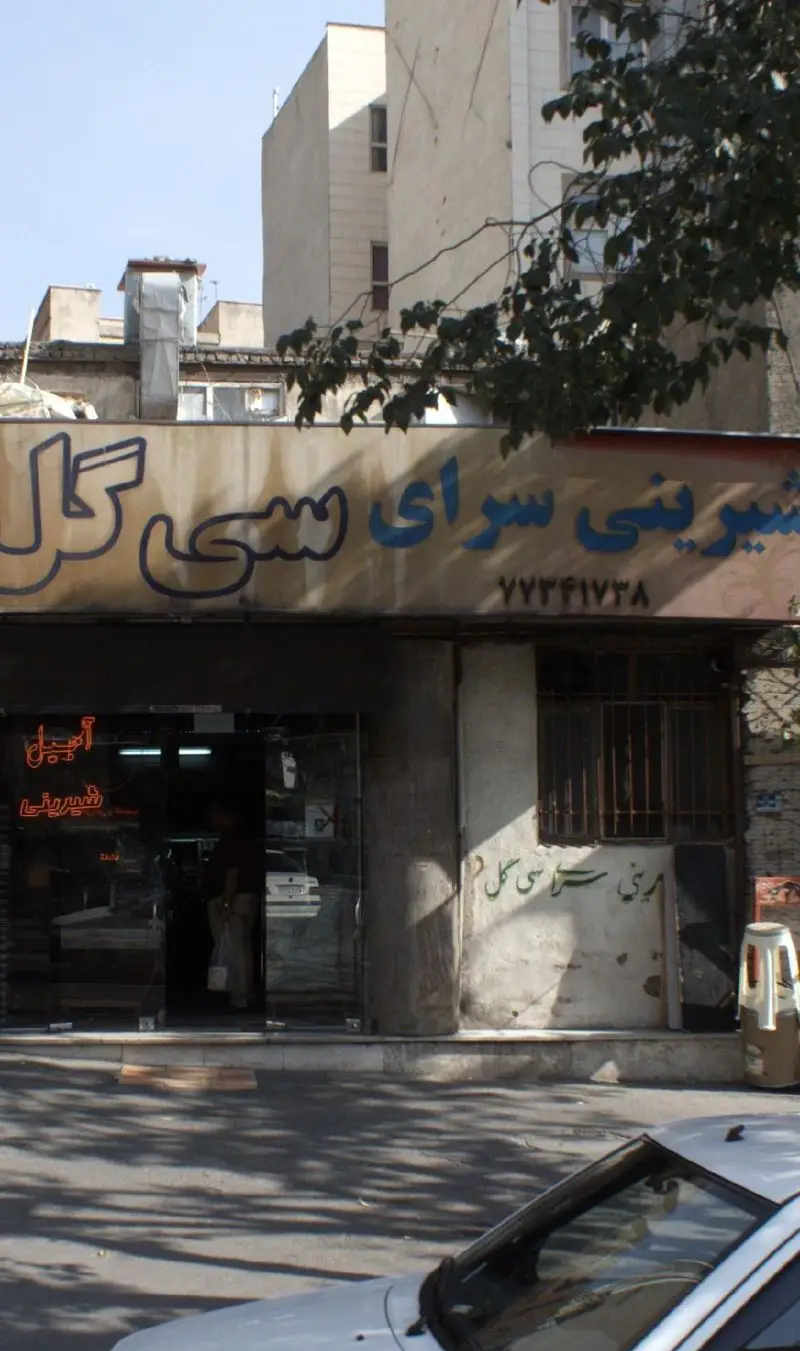 فروشگاه شیرینی سرای سی گل در تهران، نمای بیرونی با تابلوی مشخص، ورودی مغازه و اطلاعات تماس ۷۷۴۴۱۷۳۸ برای خرید انواع شیرینی و آجیل.