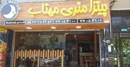 تصویری از نمای بیرونی فست فود و پیتزا متری مهتاب با تابلو بزرگ، لوگو ماه و تلفن های تماس، یک مکان عالی برای تجربه پیتزا.