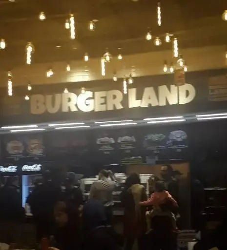 تصویر محیط داخلی فست فود برگرلند در شب با حضور مشتریان شلوغ، منوی متنوع و نورپردازی دلنشین، مکانی ایده‌آل برای تجربه برگر.