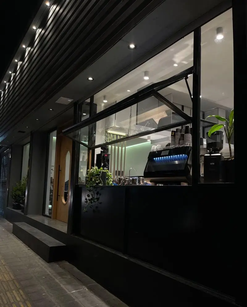 نمای بیرونی کافه بردوتی در شب، با طراحی مدرن، پنجره‌های بزرگ، دستگاه اسپرسو حرفه‌ای و نورپردازی جذاب و دلنشین.