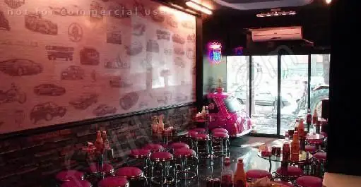 فضای داخلی جذاب رستوران گاراژ گریل با دکوراسیون منحصربه‌فرد با تم خودرو و ماشین صورتی وسط سالن، میز و صندلی‌های شیک برای مشتریان.