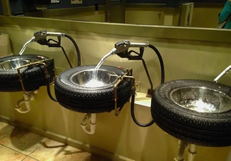 حمام رستوران Garage Grill با سینک‌های منحصر به فرد ساخته‌شده از تایر خودرو و شیرآلاتی به شکل پمپ بنزین. دکور با تم خودرویی برای تجربه‌ای متفاوت و خاص.