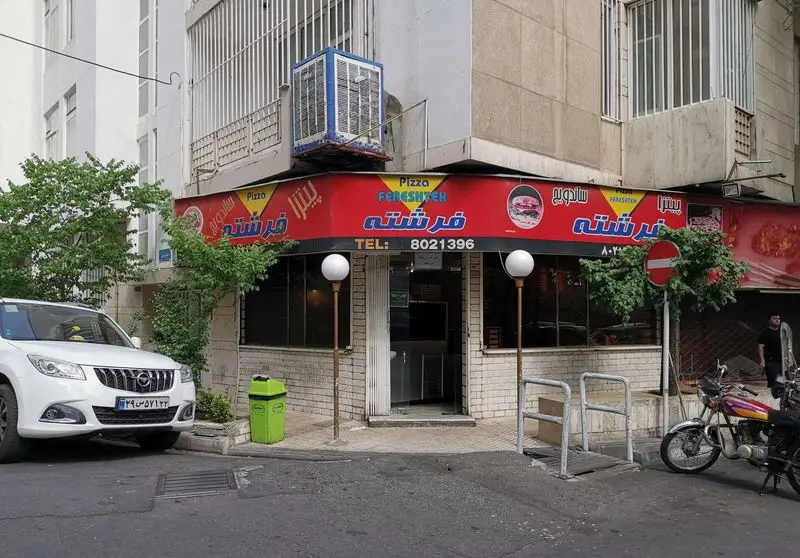 پیتزا فرشته، فست فود معروف با تابلوی قرمز و آبی، ارائه دهنده انواع پیتزا و ساندویچ. تلفن تماس جهت سفارش: 8021396