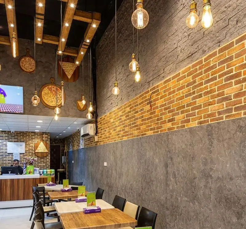 دکوراسیون داخلی رستوران سیب با طراحی مدرن، دیوارهای آجری، نورپردازی گرم، میز و صندلی‌های راحت و فضایی دلنشین برای سرو پیتزا.