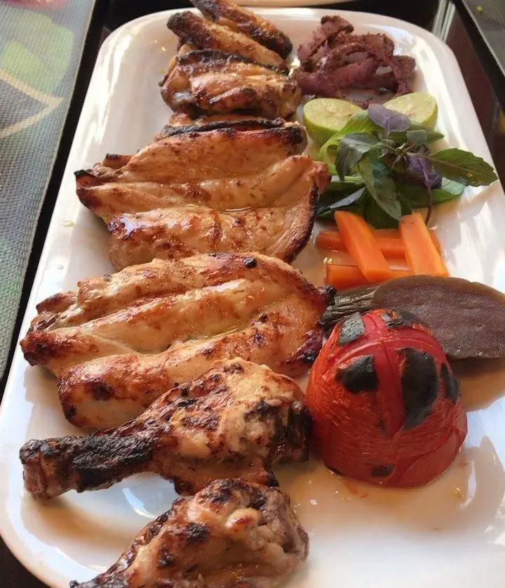 بشقاب کباب مرغ شامل بال، فیله و ران کبابی به همراه گوجه، لیمو، هویج و سبزی تازه در رستوران شیرین پلو. غذای ایرانی لذیذ.