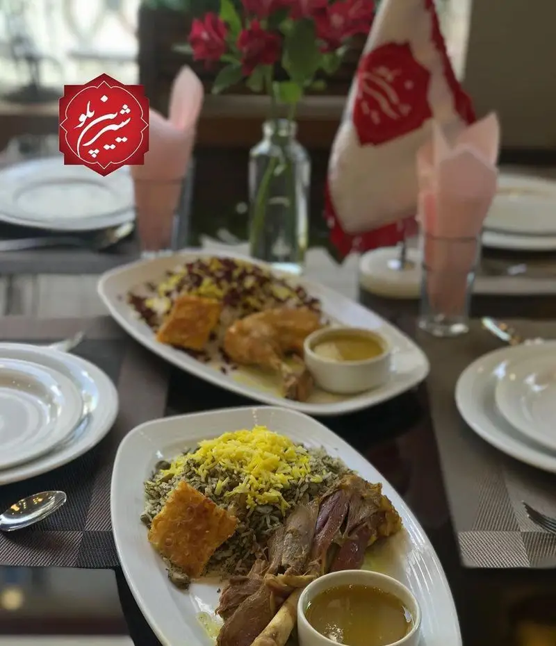 نمای میز رستوران شیرین پلو با دو پرس غذای لذیذ ایرانی: باقالی پلو با گردن و زرشک پلو با مرغ، همراه با ته دیگ زعفرانی و مخلفات خوشمزه.
