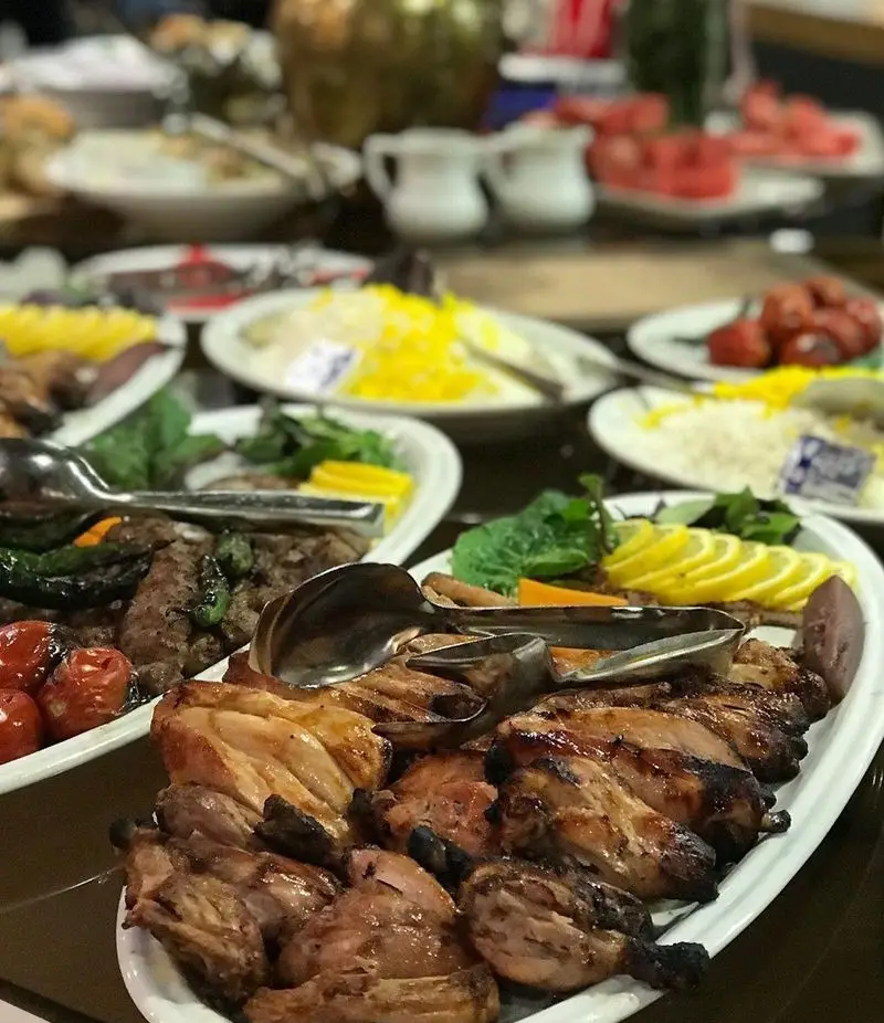 میز پر از غذاهای لذیذ ایرانی در رستوران شیرین پلو شامل چلوکباب، جوجه کباب، برنج زعفرانی و مخلفات تازه برای ضیافتی بی‌نظیر.