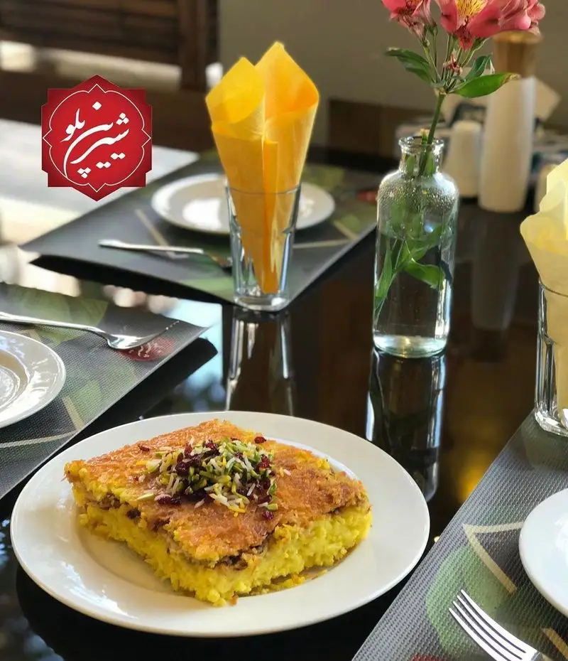 یک بشقاب ته چین زعفرانی و خوشمزه از رستوران شیرین پلو با زرشک و پسته در محیطی شیک و دلنشین. بهترین تجربه غذای اصیل ایرانی.