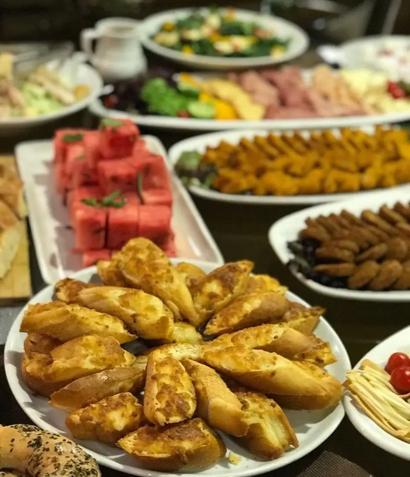 بوفه مفصل و متنوع رستوران شیرین پلو، شامل نان سیر برشته، هندوانه تازه، انواع سالاد و خوراک های لذیذ برای تجربه ای دلپذیر.