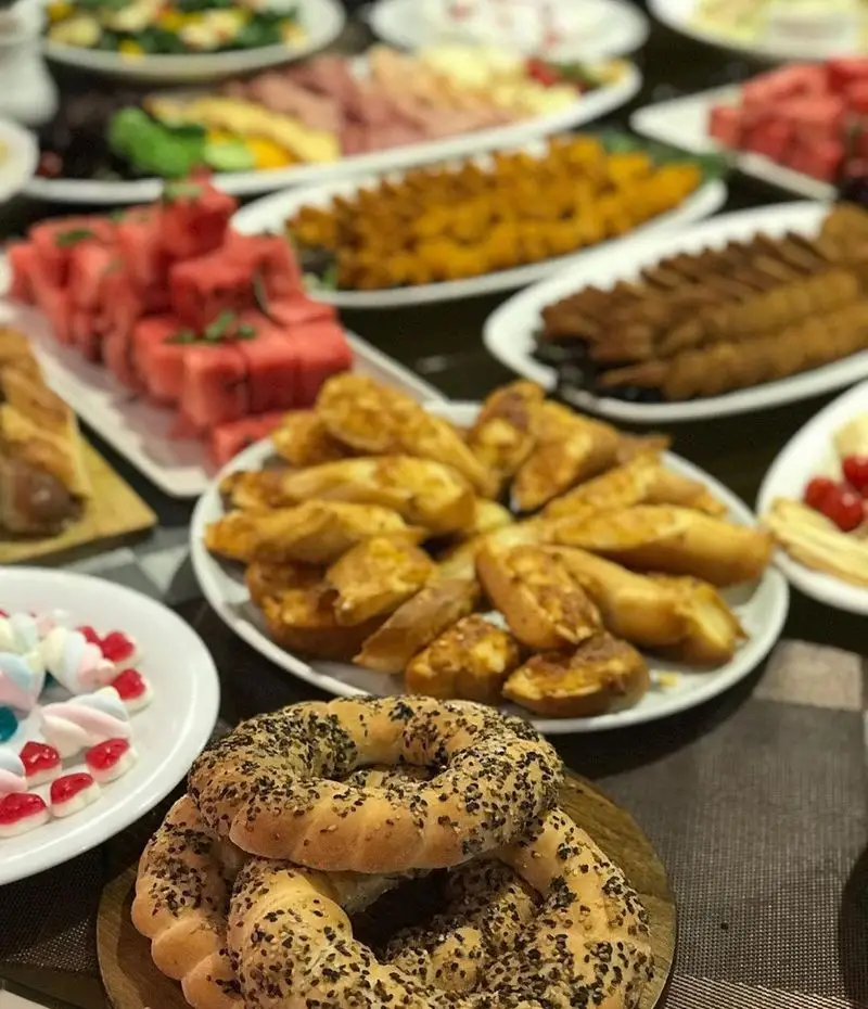 سفره پربار و اشتهاآور رستوران شیرین پلو: نان سیمیت کنجدی، نان سیر برشته، کباب‌های چوبی، هندوانه تازه و دسر‌های متنوع.