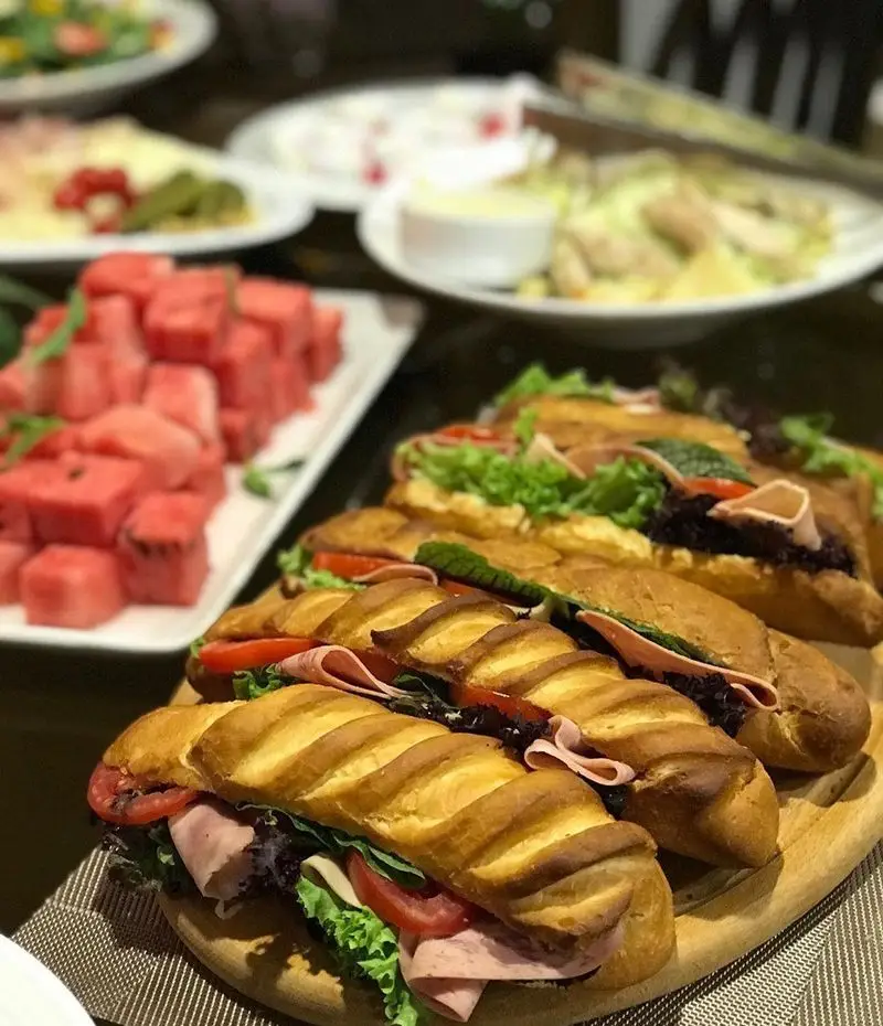 ساندویچ‌های باگت کالباس و سبزیجات تازه، شامل کاهو و گوجه، از رستوران شیرین پلو. در بوفه هندوانه و سالادهای متنوع نیز موجود است.