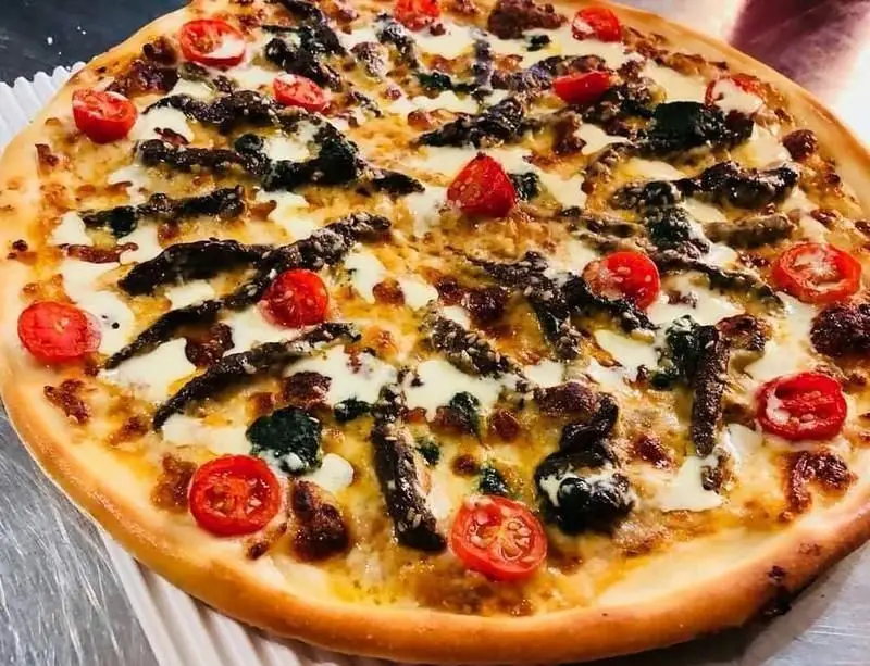 پیتزای ایتالیایی لذیذ رستوران ایتالیایی مارینو با خمیر طلایی، پنیر موزارلا آب‌شده، گوجه گیلاسی، بادمجان و سبزیجات.
