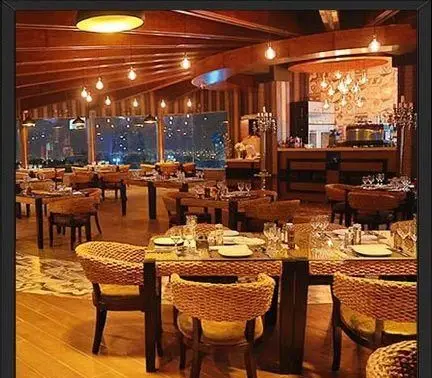 فضای داخلی رستوران ایتالیایی مارینو با دکوراسیون چوبی گرم، میزهای چیدمان شده و صندلی‌های حصیری. محیطی دنج و شیک برای یک شام فراموش‌نشدنی با منظره‌ای زیبا از شهر.