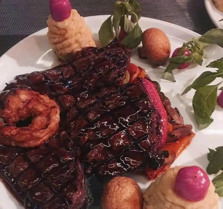 بشقاب استیک گریل ممتاز با سس براق، میگوی بزرگ، پوره و سبزیجات تازه در رستوران ایتالیایی مارینو. غذایی خوشمزه و اصیل.