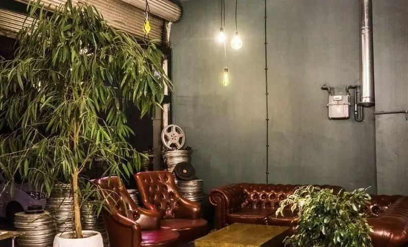 دکوراسیون داخلی دلنشین رد کافه با مبلمان چرم، گیاهان سرسبز و نورپردازی صنعتی. فضایی گرم و دوستانه برای تجربه ای متفاوت.