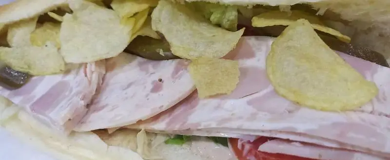 تصویری جذاب از یک ساندویچ فست فود لاکچری؛ شامل لایه‌های ژامبون مرغوب، کاهو، خیارشور و چیپس ترد برای طعمی بی‌نظیر و تجربه‌ای خاص.