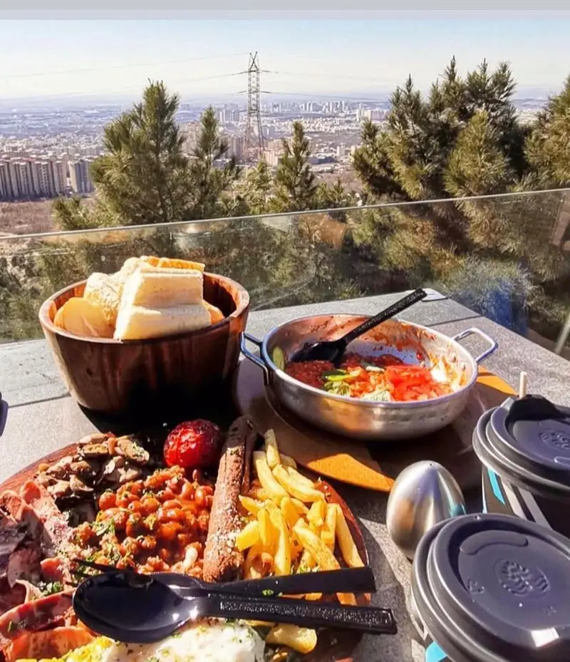 صبحانه دلپذیر در کافه رستوران سیتی تراس، شامل انواع غذاها با منظره پانورامای شهر از تراس کوهستانی.