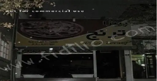 نمای بیرونی و سردر تیره فست فود ترنج در شب، با تابلویی بزرگ که یک پیتزا خوشمزه و نام "ترنج" را به فارسی و انگلیسی نمایش می‌دهد.