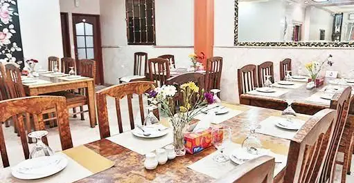 فضای داخلی دنج رستوران ایرانی تواضع با میز و صندلی‌های چوبی شیک، آماده پذیرایی از مهمانان برای تجربه غذای اصیل ایرانی.