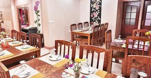 فضای داخلی رستوران ایرانی تواضع با دکوراسیون چوبی گرم، چیدمان منظم میز و صندلی و تزیینات گل، آماده برای سرو غذای اصیل ایرانی.