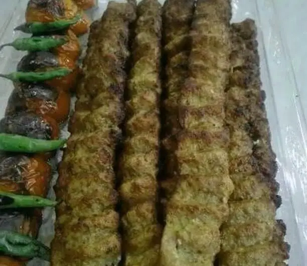 سفارش کباب کوبیده لذیذ رستوران ایرانی تواضع با سیخ‌های گوشت تازه و کبابی، همراه با گوجه و فلفل سبز، یک غذای اصیل و دلپذیر.