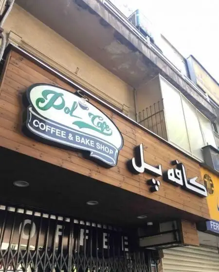 نمای بیرونی کافه پل، یک کافه و شیرینی‌فروشی با تابلوی سبز و سفید Pol Cafe و نوشته Coffee & Bake Shop بر روی نمای چوبی جذاب آن.