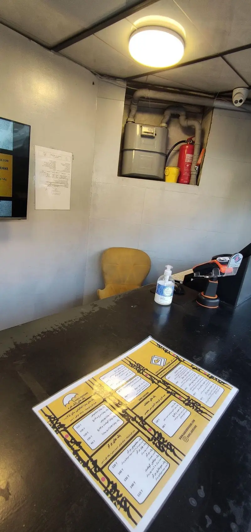 میز و منوی فست فود کاریز کوچیکه با قیمت غذاها، دستگاه پرداخت الکترونیک و ضدعفونی کننده دست. محیط کاریز کوچیکه.