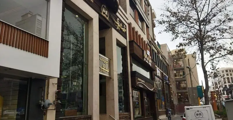 نمای بیرونی رستوران شمشیری، با تابلوی آشپزخانه شمشیری و ورودی جذاب، در کنار خیابان شهری با درخت و ساختمان‌های مجاور.