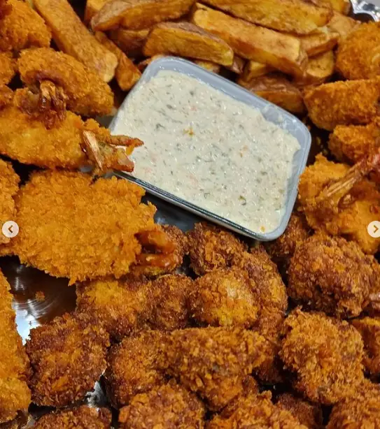 یک سینی جذاب از میگوهای سوخاری ترد، سیب زمینی‌های وج طلایی و تکه‌های سوخاری متنوع به همراه سس مخصوص رستوران شمشیری.