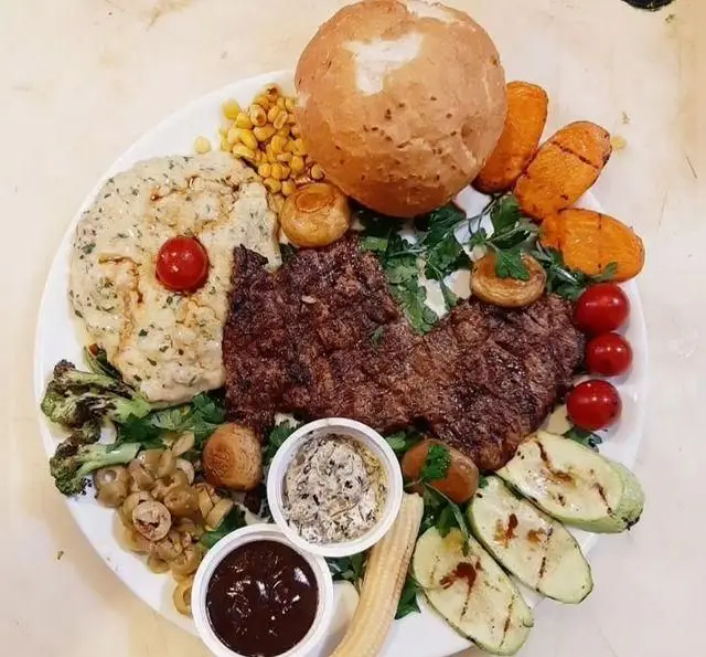 بشقاب استیک کامل و خوشمزه سفره خانه خیام؛ با استیک گریل، پوره سیب‌زمینی، سبزیجات متنوع (هویج، کدو، بروکلی)، ذرت، قارچ، زیتون و نان گرد.