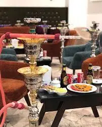 تصویری از فضای دلنشین و دنج کافه عربی یاقوت با قلیان‌های مجلل، میز مملو از نوشیدنی‌ها، غذا و محیطی ایده‌آل برای دورهمی‌ها.