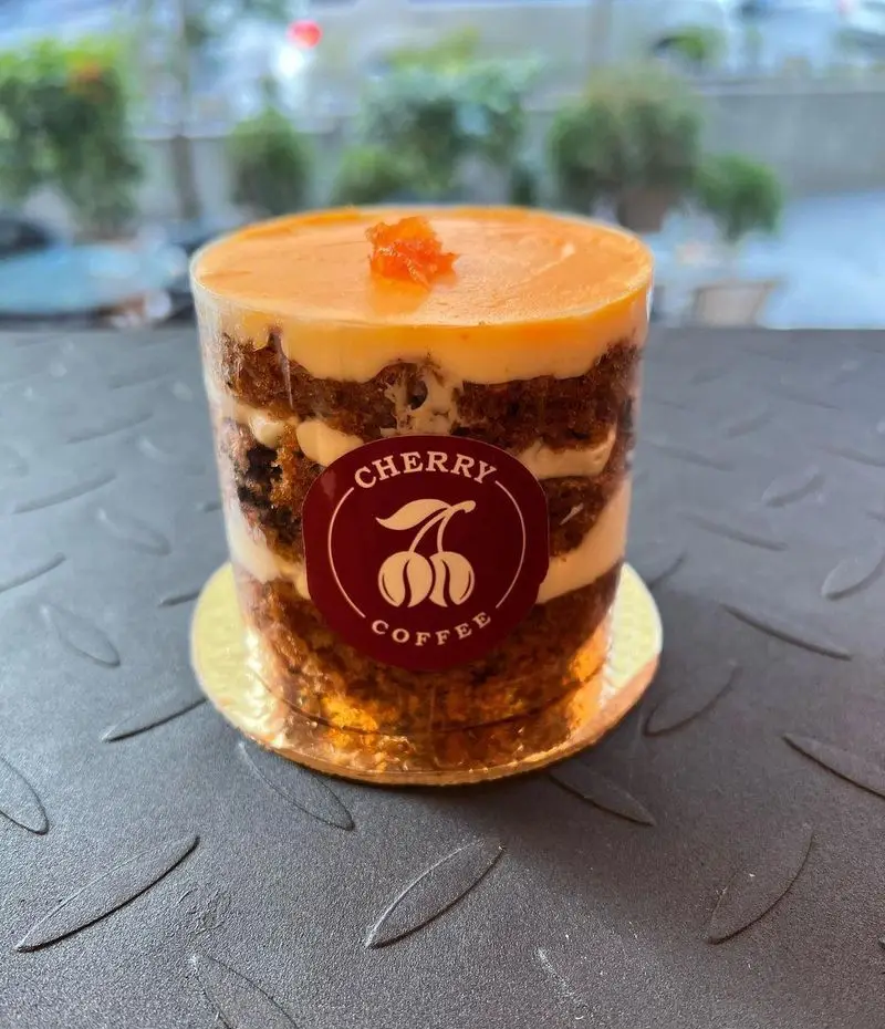 تصویر دسر کیک لایه ای جذاب کافه چری با روکش نارنجی و برچسب Cherry Coffee. طعم اصیل و کیفیت برتر در کافه چری