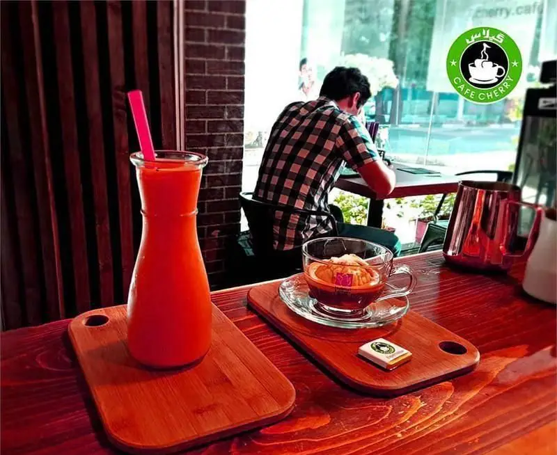 فضای دلنشین و دنج کافه چری با نوشیدنی‌های تازه شامل آبمیوه طبیعی و قهوه خاص با دسر، سرو شده روی میز چوبی زیبا.