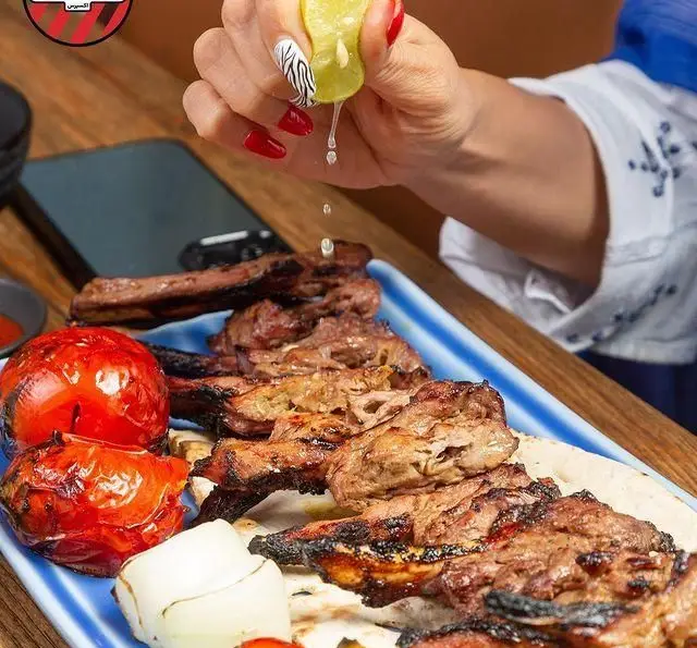 آبگیری لیموی تازه بر روی کباب‌های آبدار و خوش‌طعم کبابچی آجودانیه، همراه با گوجه و پیاز کبابی. لذت کباب ایرانی اصیل.