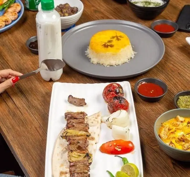 سفره‌ای دلپذیر از کباب‌های لذیذ ایرانی، چلو زعفرانی، دوغ سنتی و مخلفات متنوع در رستوران کبابچی آجودانیه.