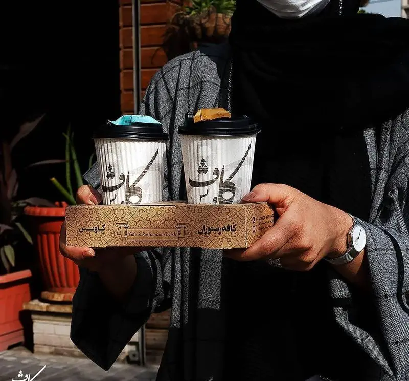دو فنجان قهوه آماده بیرون‌بر از کافه رستوران کاویش، با لوگو و نام کاویش روی سینی و لیوان‌ها، در دستان مشتری یا پیک تحویل.