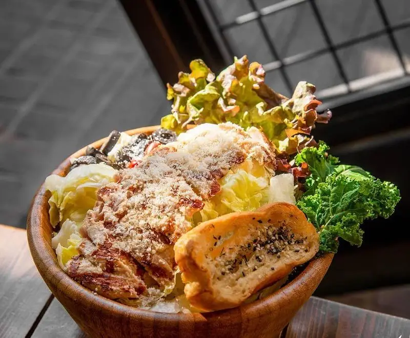 سالاد سزار مرغ گریل تازه و لذیذ کافه رستوران کاویش. شامل کاهو، مرغ گریل، پنیر پارمسان، زیتون سیاه و نان تست دانه‌دار.