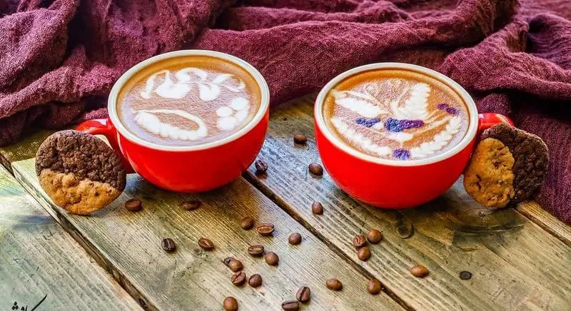 قهوه لاته آرت هنرمندانه و کوکی‌های دلپذیر در کافه رستوران کاویش، محیطی آرامش‌بخش برای لذت بردن از نوشیدنی و دسر.