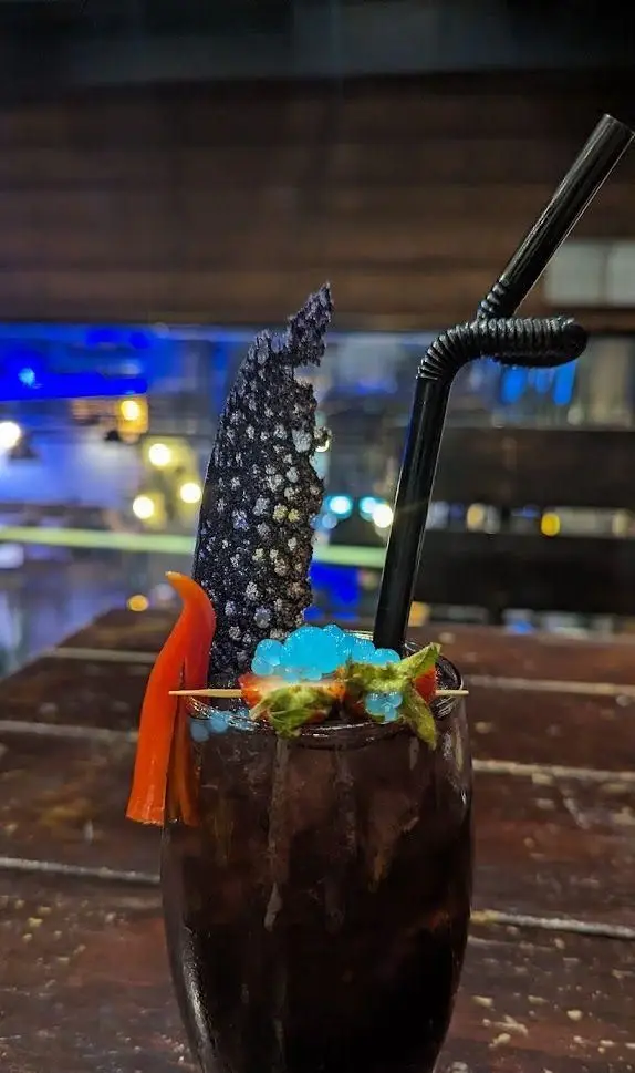 کوکتل تیره و خاص کافه رستوران کاویش با تزئینات خلاقانه توت فرنگی، حباب‌های آبی و المان‌های خوراکی منحصر به فرد