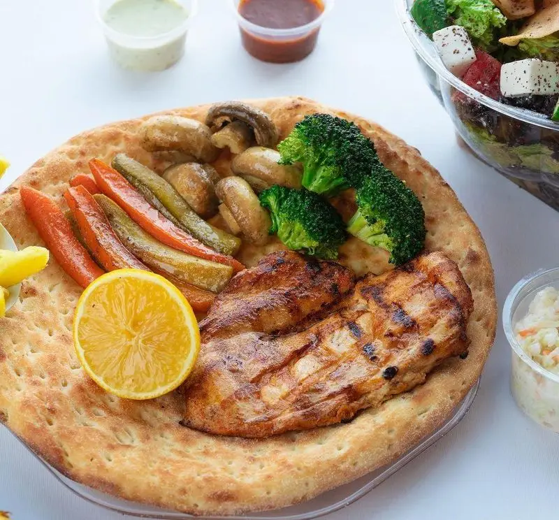 غذای سالم فست فود چیکولند: فیله مرغ گریل شده روی نان تازه با سبزیجات (هویج، بروکلی، قارچ)، لیمو، سس، سالاد و سالاد کلم.