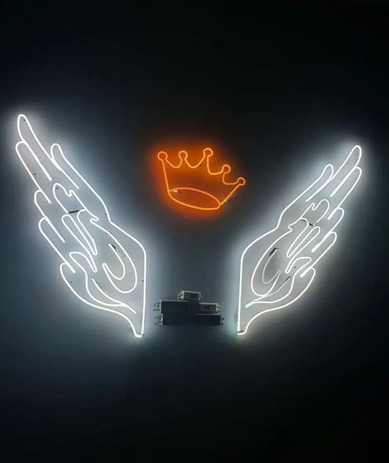 تصویر دکوراسیون داخلی رستوران فرنگی ده و ده با نئون‌های جذاب بال و تاج در زمینه تاریک. فضای مدرن و خاص.