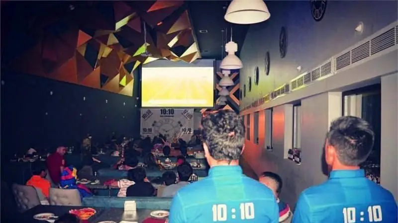 فضای داخلی دنج رستوران فرنگی ده و ده، مملو از مشتریانی که در حال تماشای صفحه نمایش بزرگ هستند و از دورهمی خود لذت میبرند.