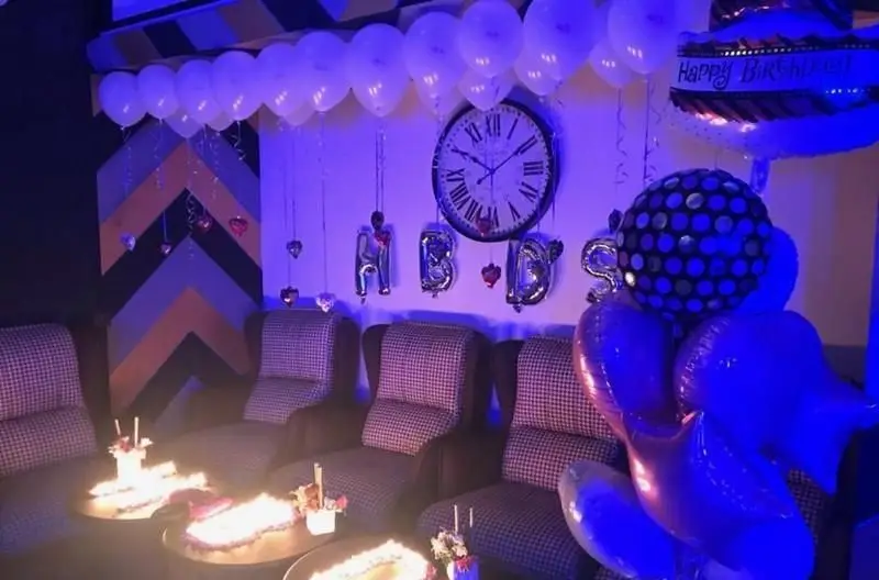 دکوراسیون جذاب و مدرن رستوران فرنگی ده و ده برای جشن تولد، با بالون‌های سفید، نورپردازی آبی و فضایی دلنشین و خاطره‌انگیز.