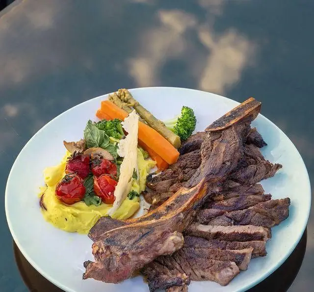 لذت طعم استیک دنده گاو گریل شده با سبزیجات تازه، پوره و گوجه در بشقابی لوکس از کشتی رستوران رویال لانژ. انتخابی عالی برای شام.